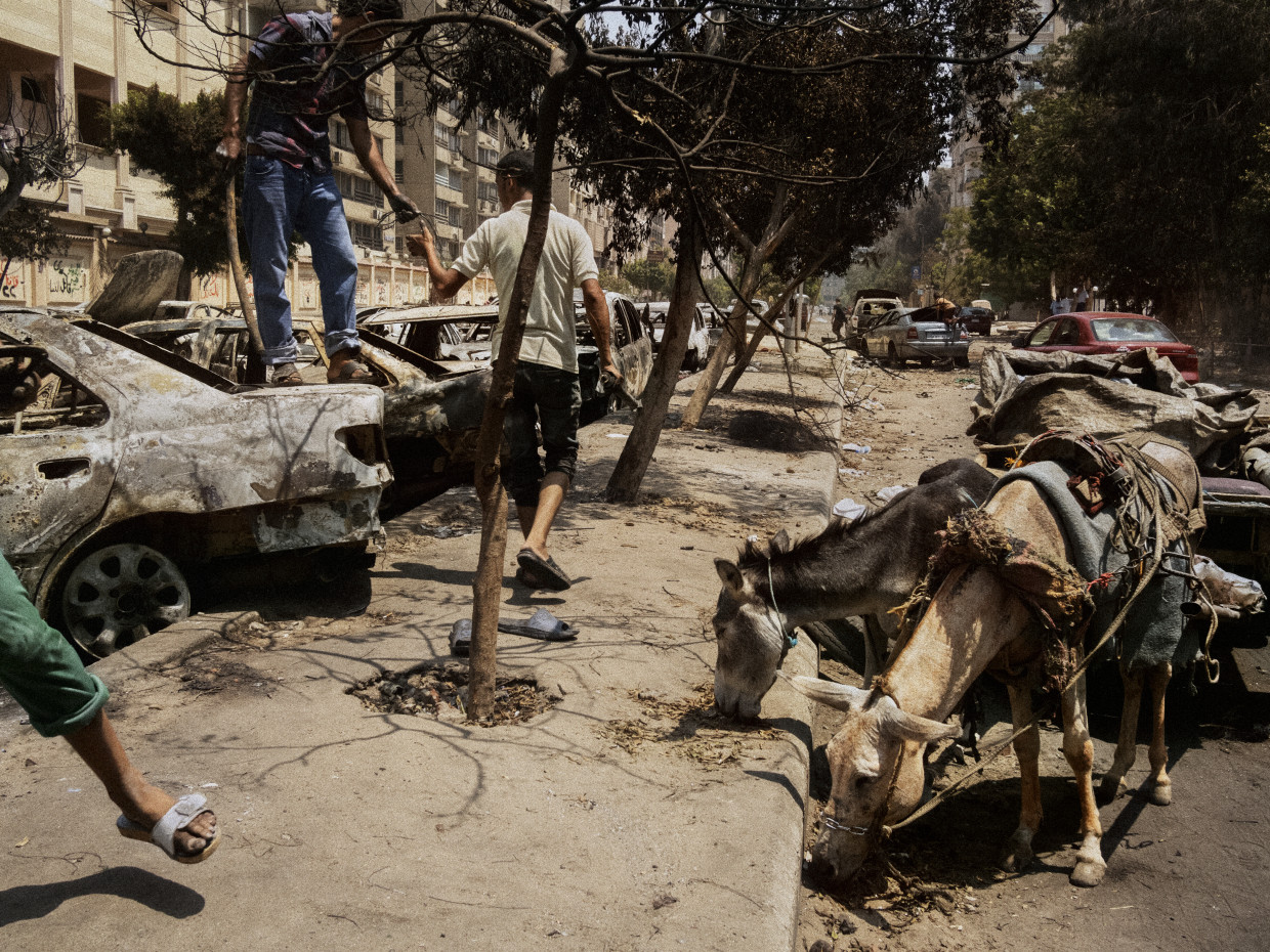 Cairo, Egypt. December, 2013. Men collect scrap metal from burned vehicles damaged during the Rabaa massacre of supporters of the Muslim Brotherhood.