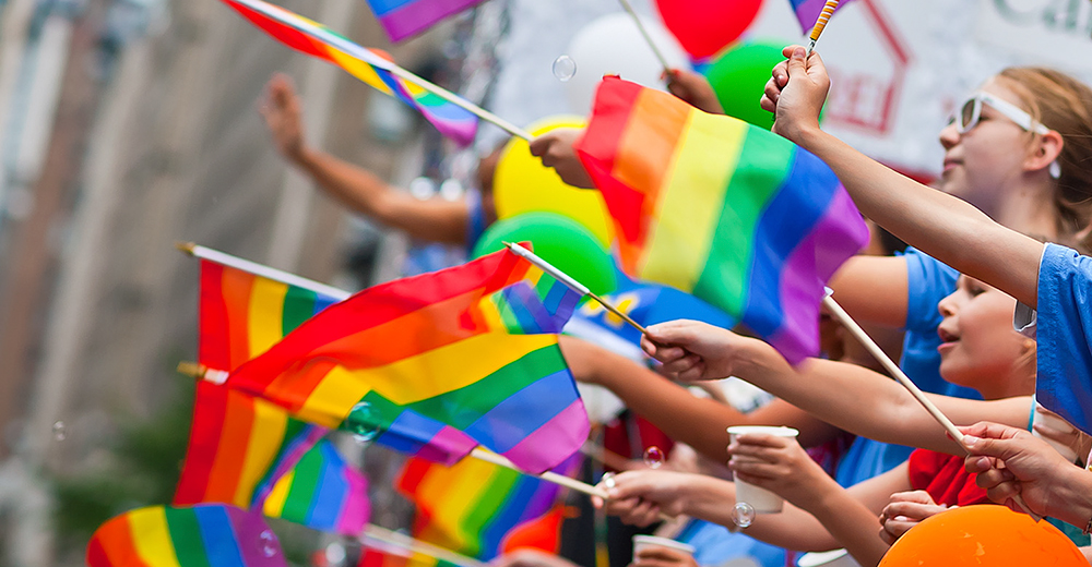 People holding rainbow color flag 