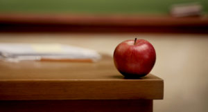 Red apple on teacher's desk.