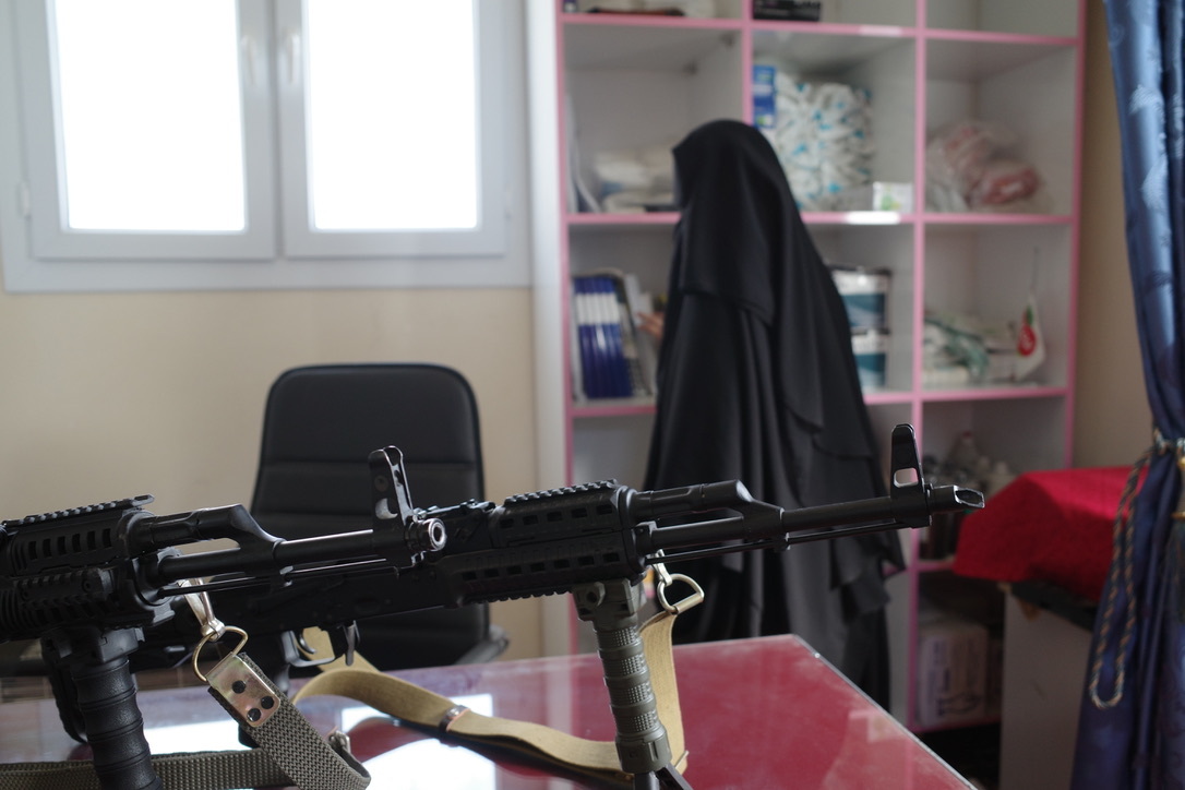 A woman stands next to a gun on a table